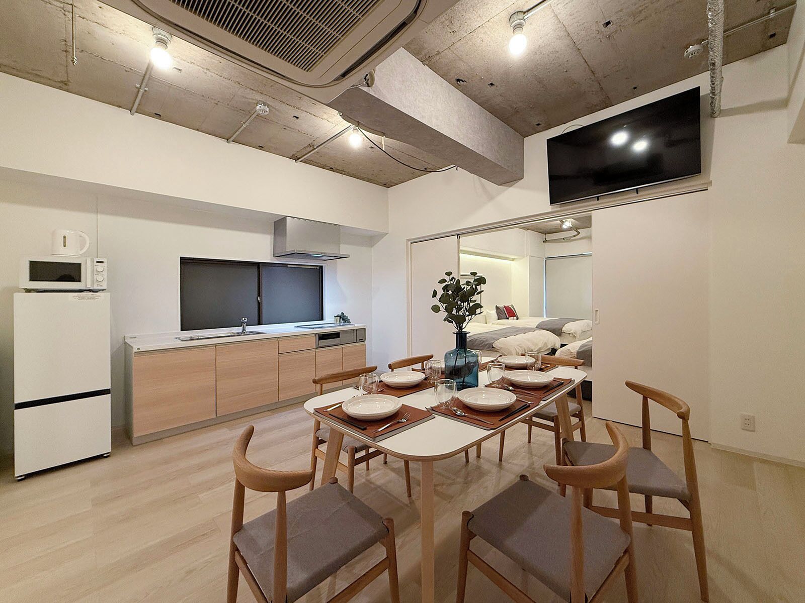 A modern kitchen with a dining area, a flat-screen TV, and a large mirror.