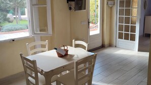 A dining area with a table and chairs, a television mounted on the wall, and a door leading outside.