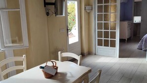 A dining area with a table and chairs, a window with a view of greenery, and a door leading to another room.