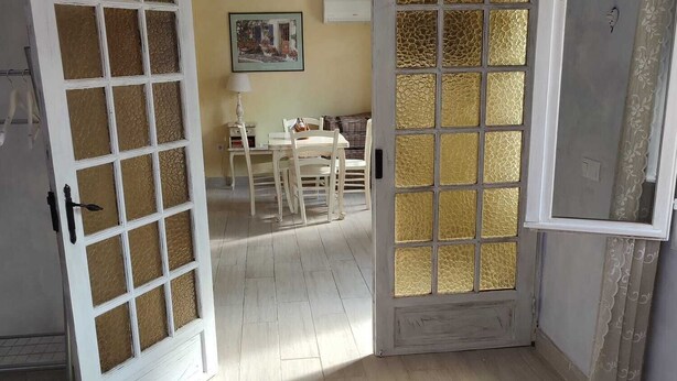 A bedroom with a bed, a door leading to a dining area, and a view of the dining area.