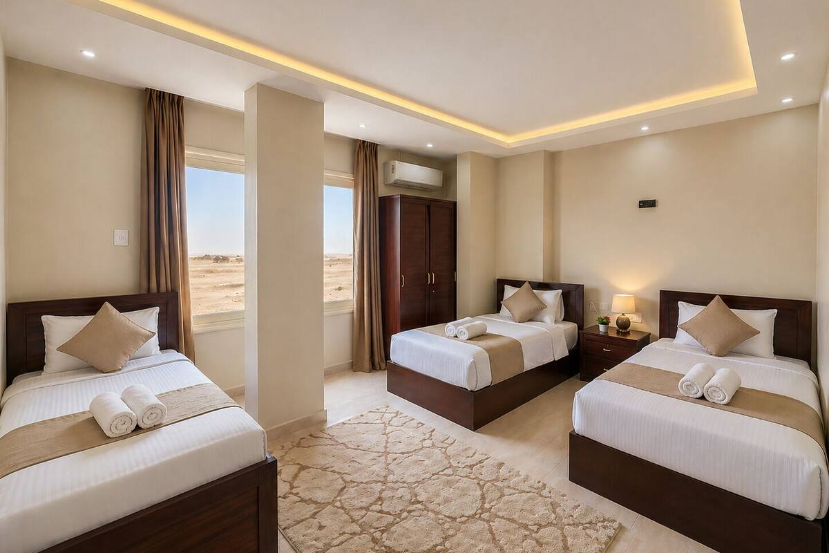 Habitación de hotel con dos camas, un ventanal grande, un equipo de aire acondicionado central y una alfombra estampada.