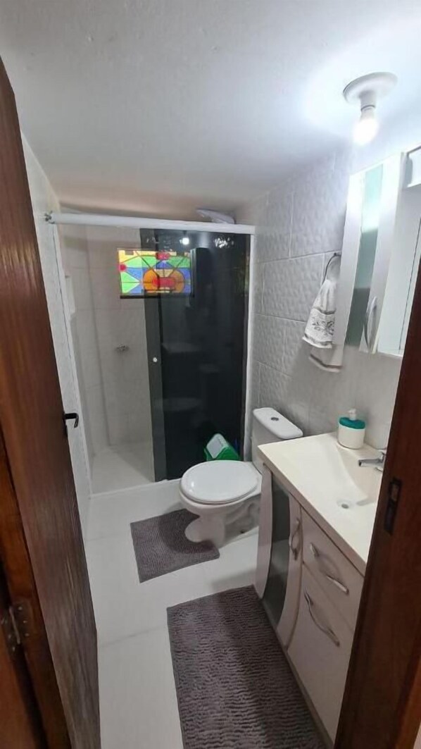 A bathroom with a toilet, sink, and shower area. - Refugio Bela Ilha (Florianópolis)