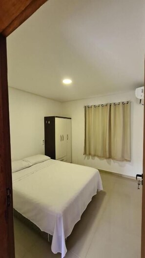 A bedroom with a bed, a wardrobe, and a window with curtains. - Refugio Bela Ilha (Florianópolis)