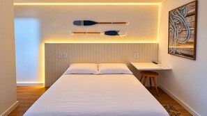 A hotel room with a bed, a desk, and two paddles on the wall. - Refugio Bela Ilha (Florianópolis)