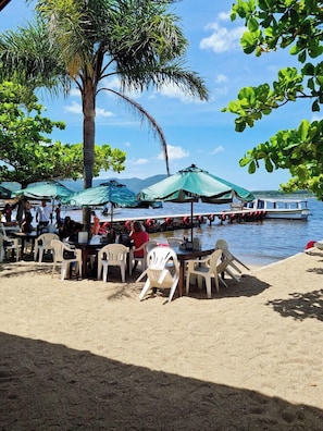 A beachside restaurant with outdoor seating, umbrellas, and a view of the water. - Refugio Bela Ilha (Florianópolis)