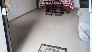 Un pequeño espacio habitable de planta libre con una mesa de comedor y sillas, un televisor montado en la pared y un felpudo que dice 'BEM-VINDO'.