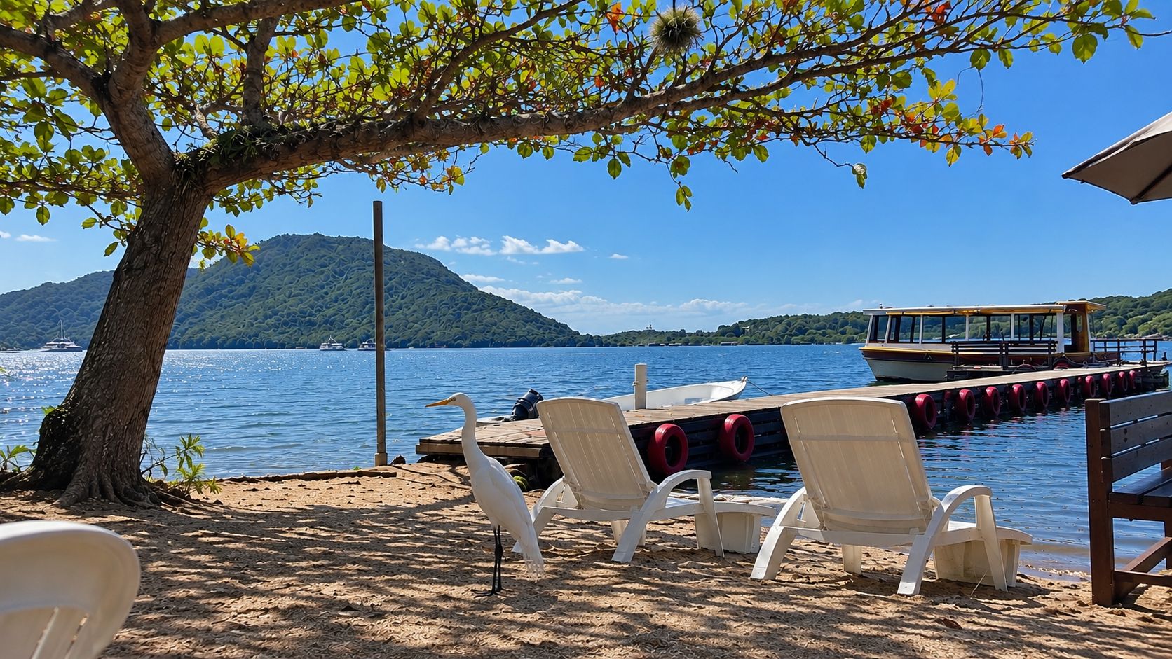 Ein Strand mit weißen Stühlen, einem Steg und einem Boot.