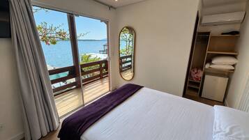 Una camera da letto con un letto, un armadio, uno specchio e vista mare tramite una porta scorrevole.