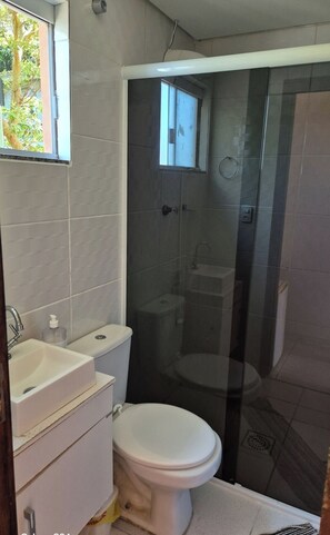 A small bathroom with a toilet, sink, and glass shower enclosure. - Refugio Bela Ilha (Florianópolis)
