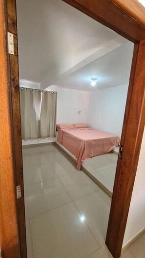A small, clean room with a single bed, a window with curtains, and a tiled floor. - Refugio Bela Ilha (Florianópolis)