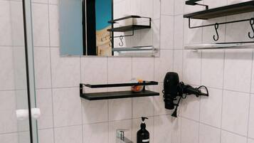 Un baño con lavamanos blanco, espejo y toalleros negros.