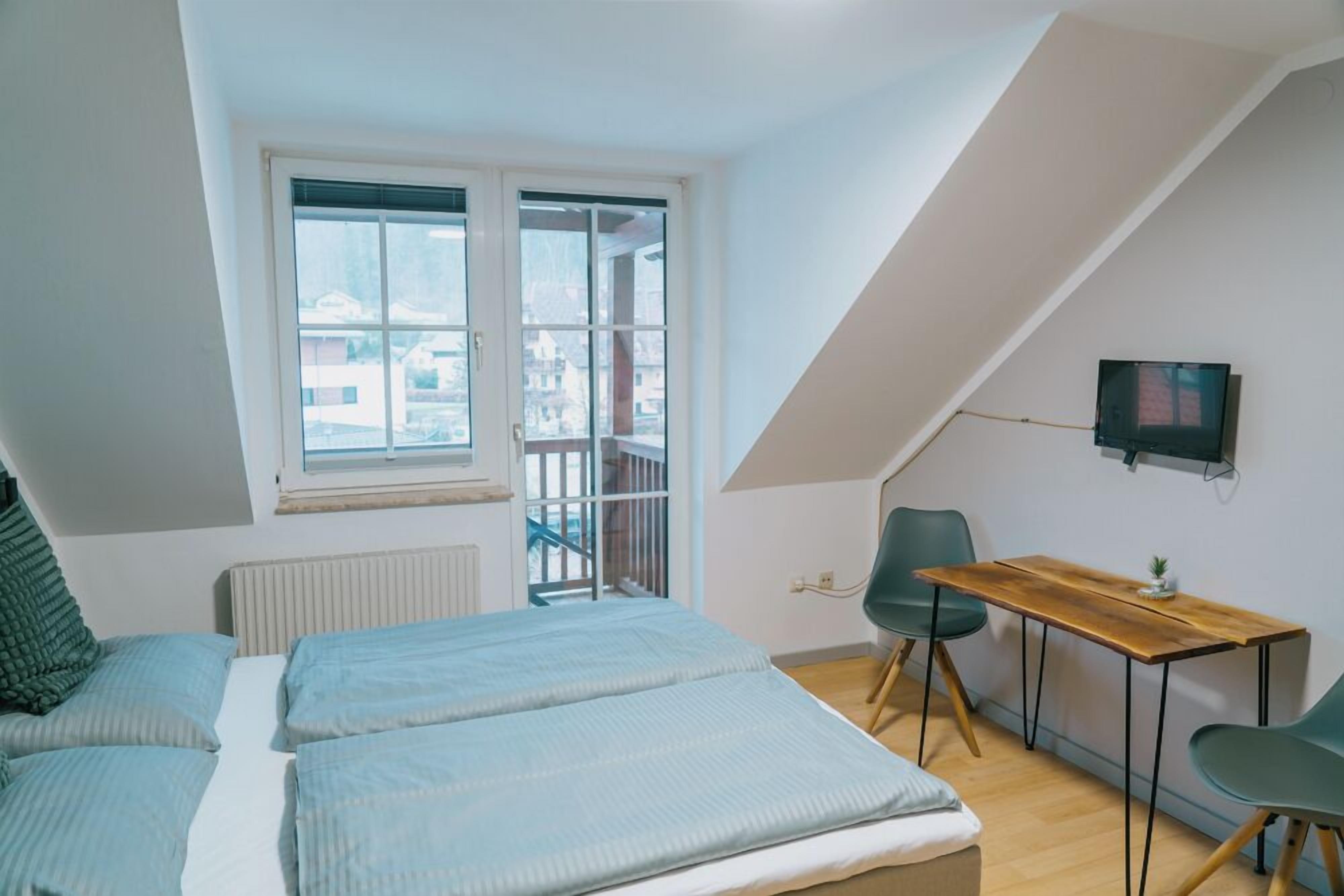 Um quarto com uma cama, uma escrivaninha e uma televisão.