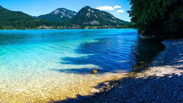 A clear lake with a pebble beach and mountains in the background. - Mountain View Salzburg - SELF CHECK-IN - Apartments (Groedig)