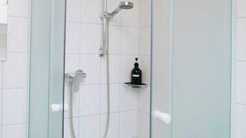 Un box de ducha con paredes de cristal, ducha de mano y grifo de mano.