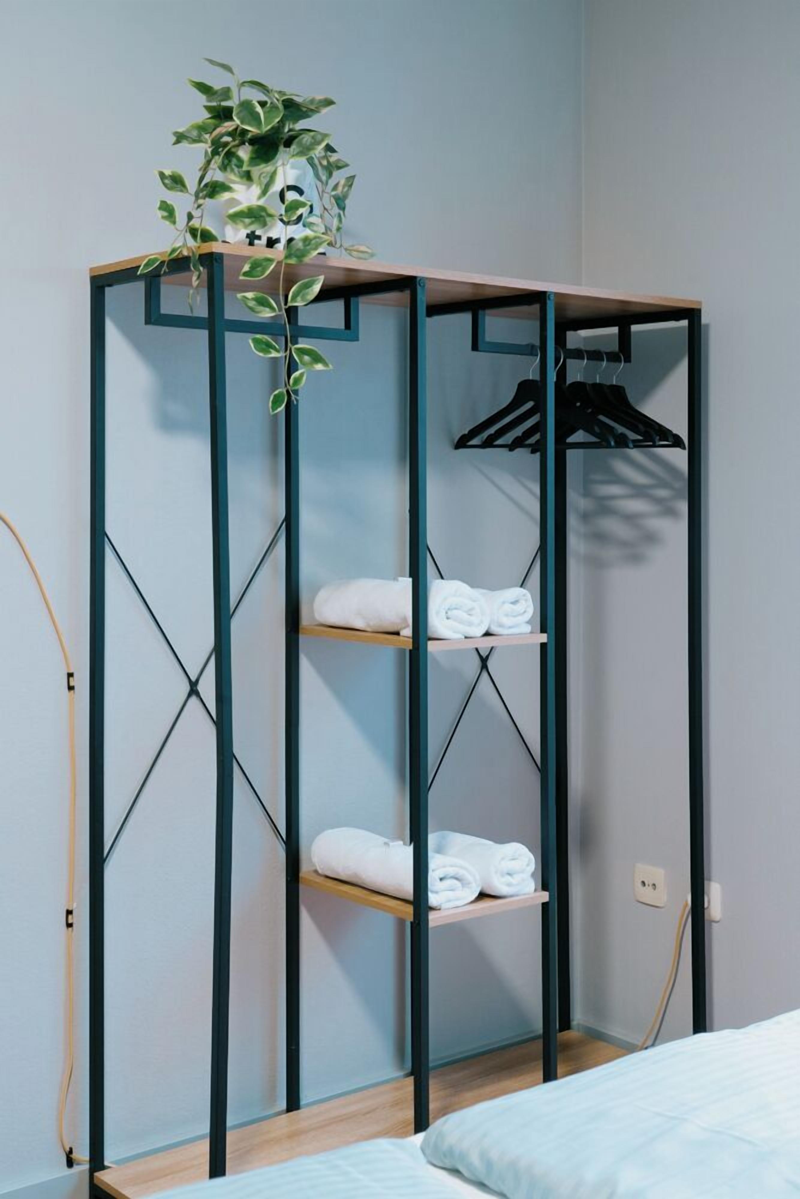 Ein Zimmer mit einem Bett, einem Holzschrank mit Regalen und einer hängenden Pflanze.