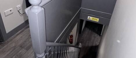 A staircase with a handrail, a door marked with the number 20, and a caution sign on the wall.