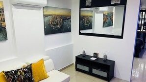 A modern living room with a white sofa, a black console table, and two paintings of cityscapes.