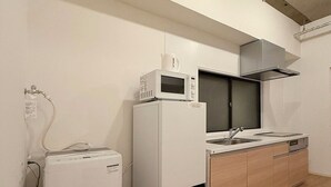 Une cuisine compacte équipée d’un four à micro-ondes, d’un petit réfrigérateur, d’un évier et d’une cuisinière.