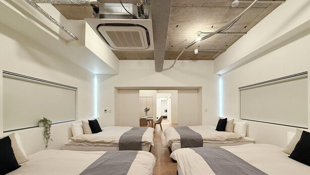 Une chambre d’hôtel avec deux lits, un ventilateur de plafond et une salle de bain visible au fond.