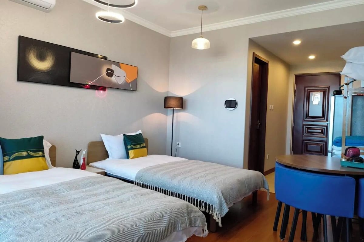 A hotel room with two beds, a TV, a desk, and a chair.