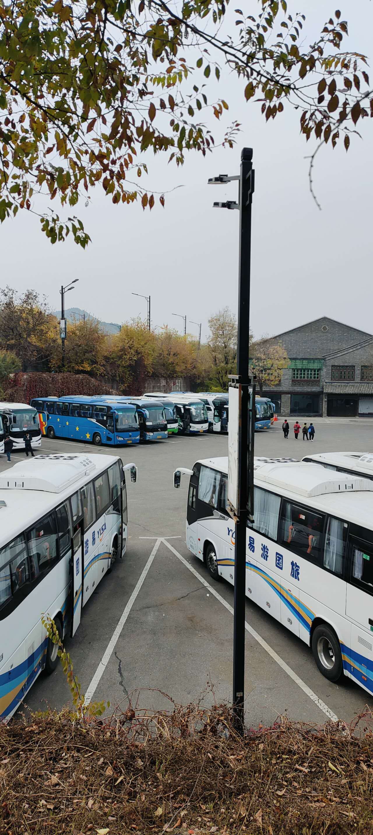 A parking lot with several buses parked.