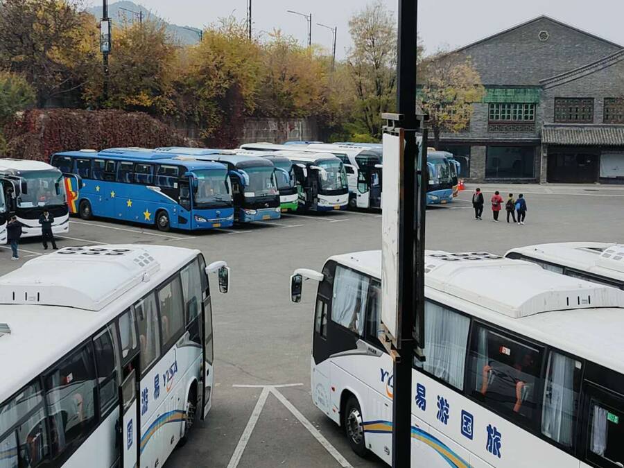 A parking lot with several buses parked.