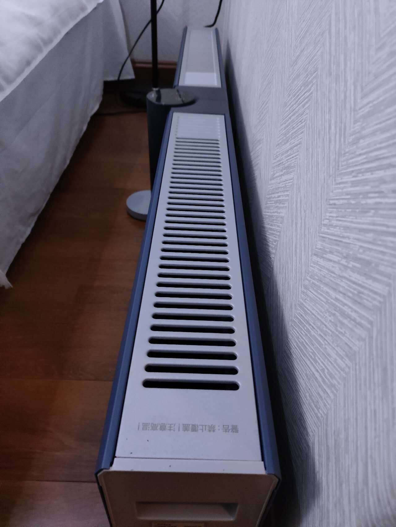 A room with a radiator, a bed, and a bedside table.