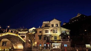 A traditional building with a stone bridge in front, illuminated by warm lights. - ATRIUM FENGZHU HOMESTAY (Miyun)