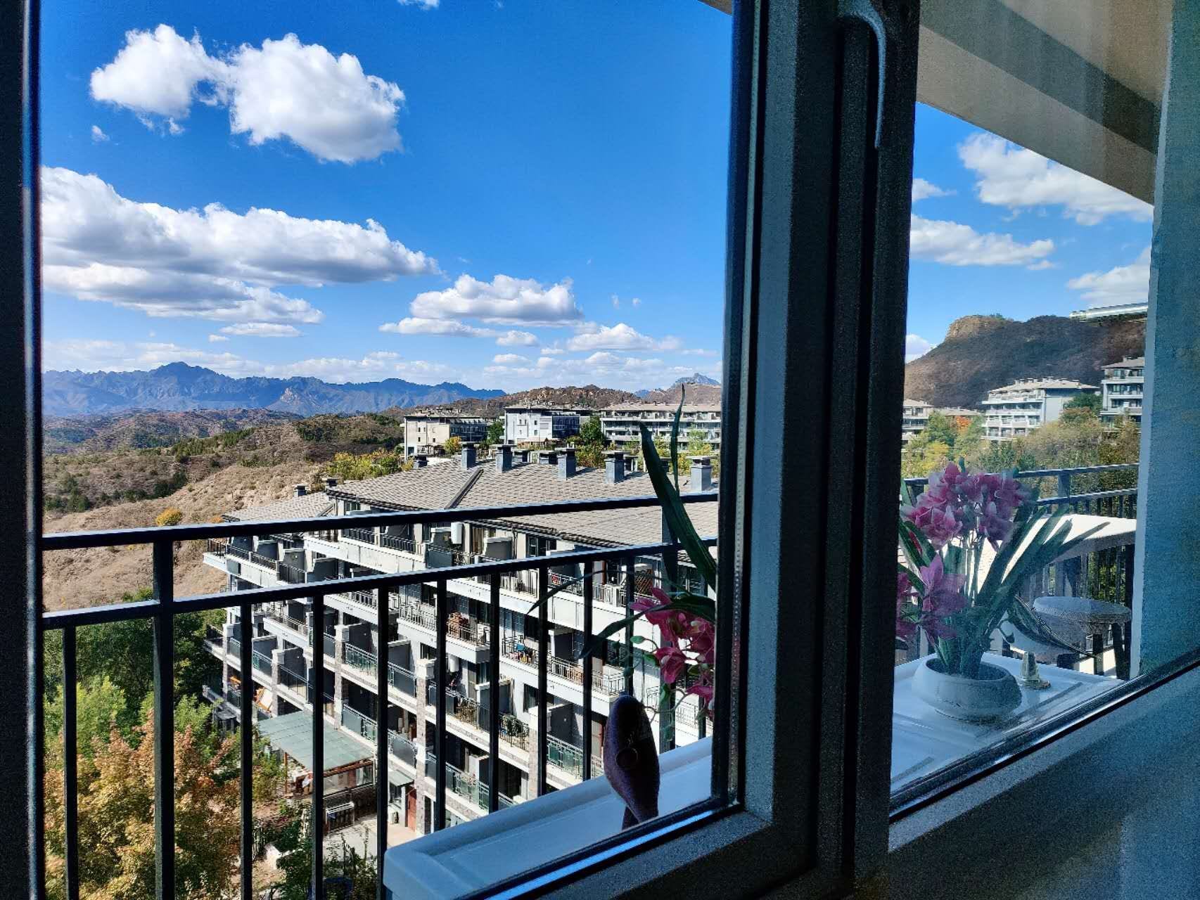 A balcony with a view of a mountainous landscape and a residential area.