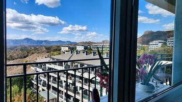 A balcony with a view of a mountainous landscape and a residential area.