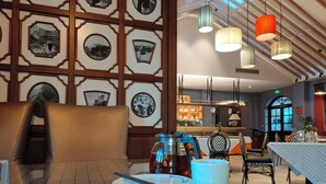 A dining area with a table set for two, a chair, and a wall decorated with framed pictures. - ATRIUM FENGZHU HOMESTAY (Miyun)