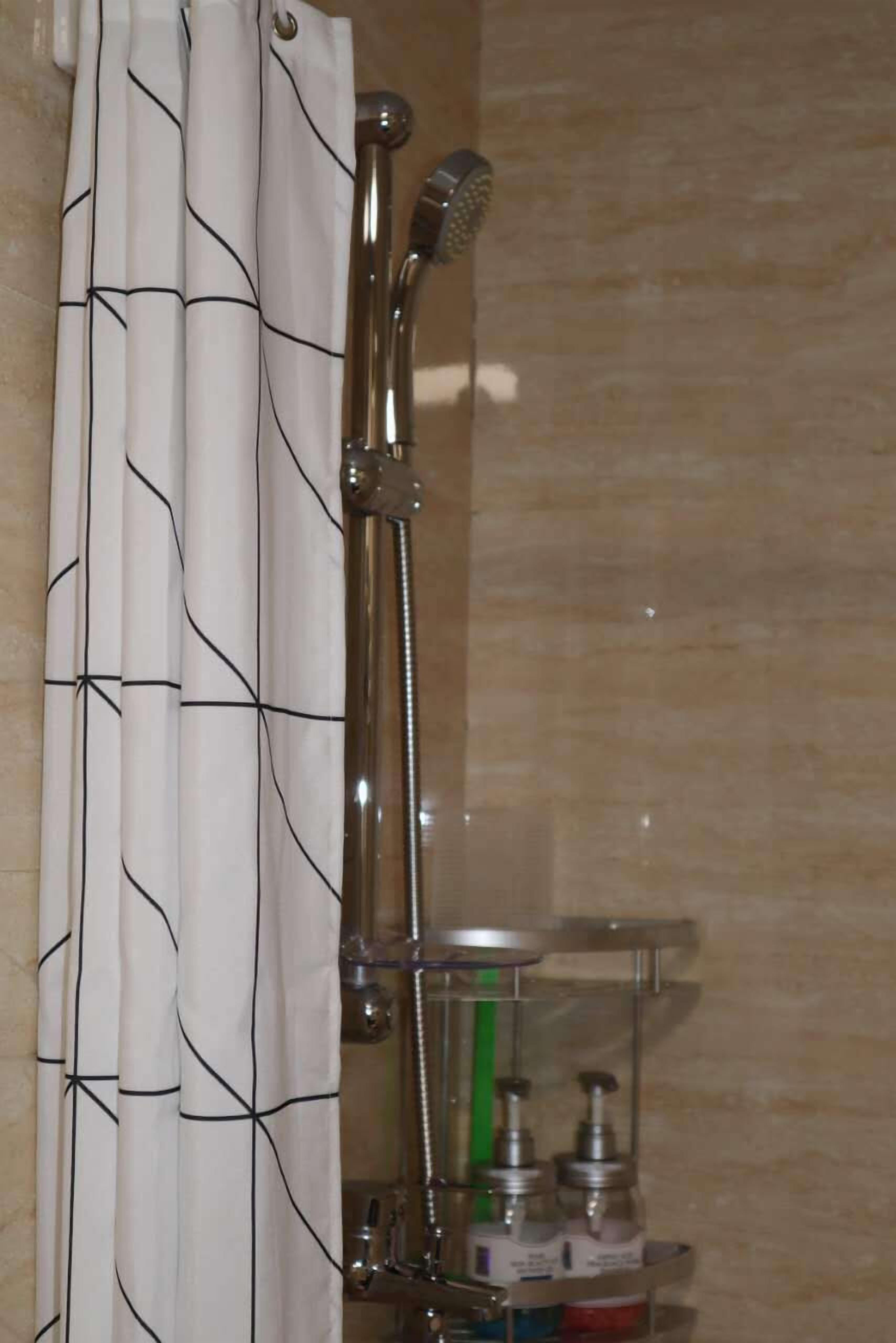 Eine Dusche mit Handbrause und Armaturen an der Wand.