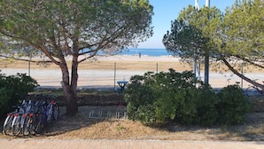 A beachside area with a fenced bike parking area, a picnic table, and a view of the sea.