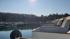 A marina with boats docked, a clear sky, and a sun shining.