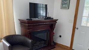 A living room with a fireplace, a television, and a door with a sign reading "LIVE LOVE LAKE".