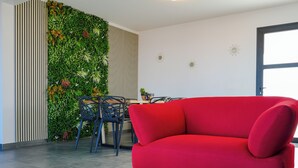 Un salon moderne avec un canapé rouge, une table à manger avec des chaises et un mur végétal vertical.
