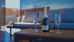Une bouteille de vin et deux verres sur une table en bois, avec un canapé et une clôture en bois en arrière-plan.