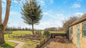 A garden with raised beds, a wooden bench, and a table with chairs.