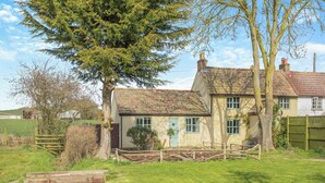 A traditional house with a tiled roof, a front garden, and a wooden fence.