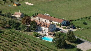 Vista aérea de una extensa propiedad con piscina, viñedo y varias edificaciones.