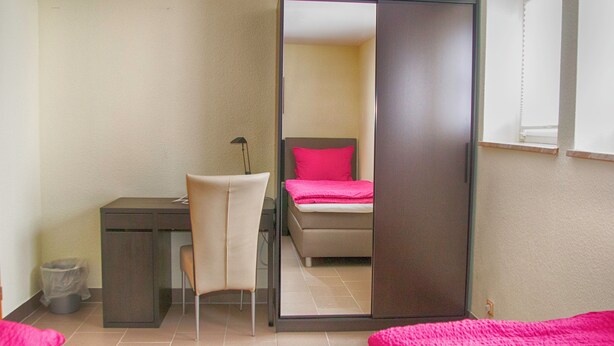 Een slaapkamer met een bed, een bureau en een stoel.