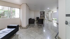 A hallway with a bench, chairs, and a staircase in the distance. - Central Studium (São Paulo)