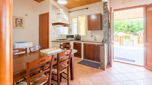 Une cuisine avec des meubles de rangement en bois, une table à manger avec des chaises, un four à micro-ondes et une cuisinière.