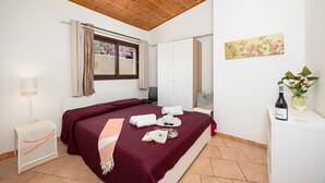 A bedroom with a wooden ceiling, a bed with a red bedspread, a bedside table with a bottle and glasses, a lamp, and a window with curtains. - Dune Giardino - Three Bedroom Villa, Sleeps 6 (Scicli)