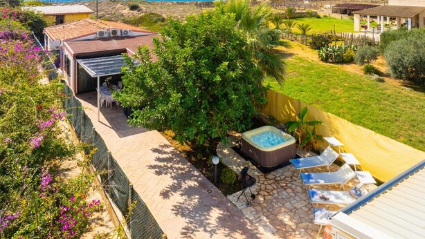 A backyard with a hot tub, outdoor seating, and a view of the ocean. - Dune Giardino - Three Bedroom Villa, Sleeps 6 (Scicli)