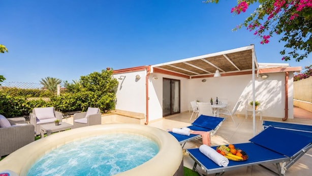 Un jacuzzi, sillas de descanso y un patio cubierto con mesa y sillas.