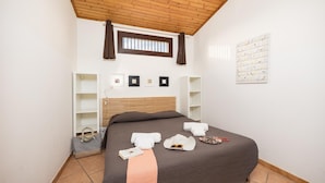 Un dormitorio con cama, ventana, armario y una pared decorada con obras de arte.