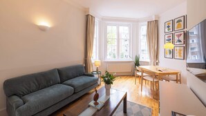 Een moderne woonkamer met een grijze bank, een houten salontafel en een eetgedeelte met tafel en stoelen.