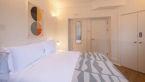 Une chambre d’hôtel avec un lit, une armoire et un miroir au mur.