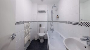 Une salle de bain moderne équipée de toilettes, d’une baignoire et d’un lavabo.